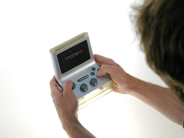 Holding A MOMA Mobile Gaming Console (2290536922) - a man holding a cell phone